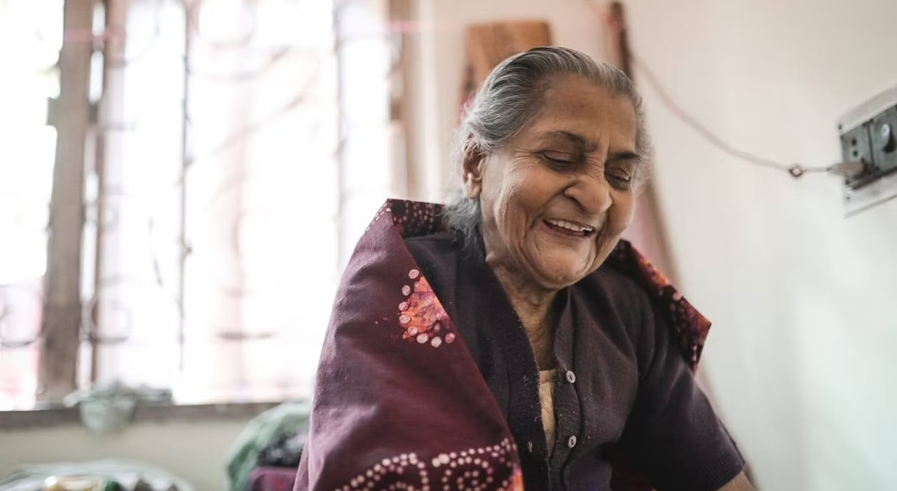 An elderly woman smiling warmly at home during a Setu Sverige Foundation community visit